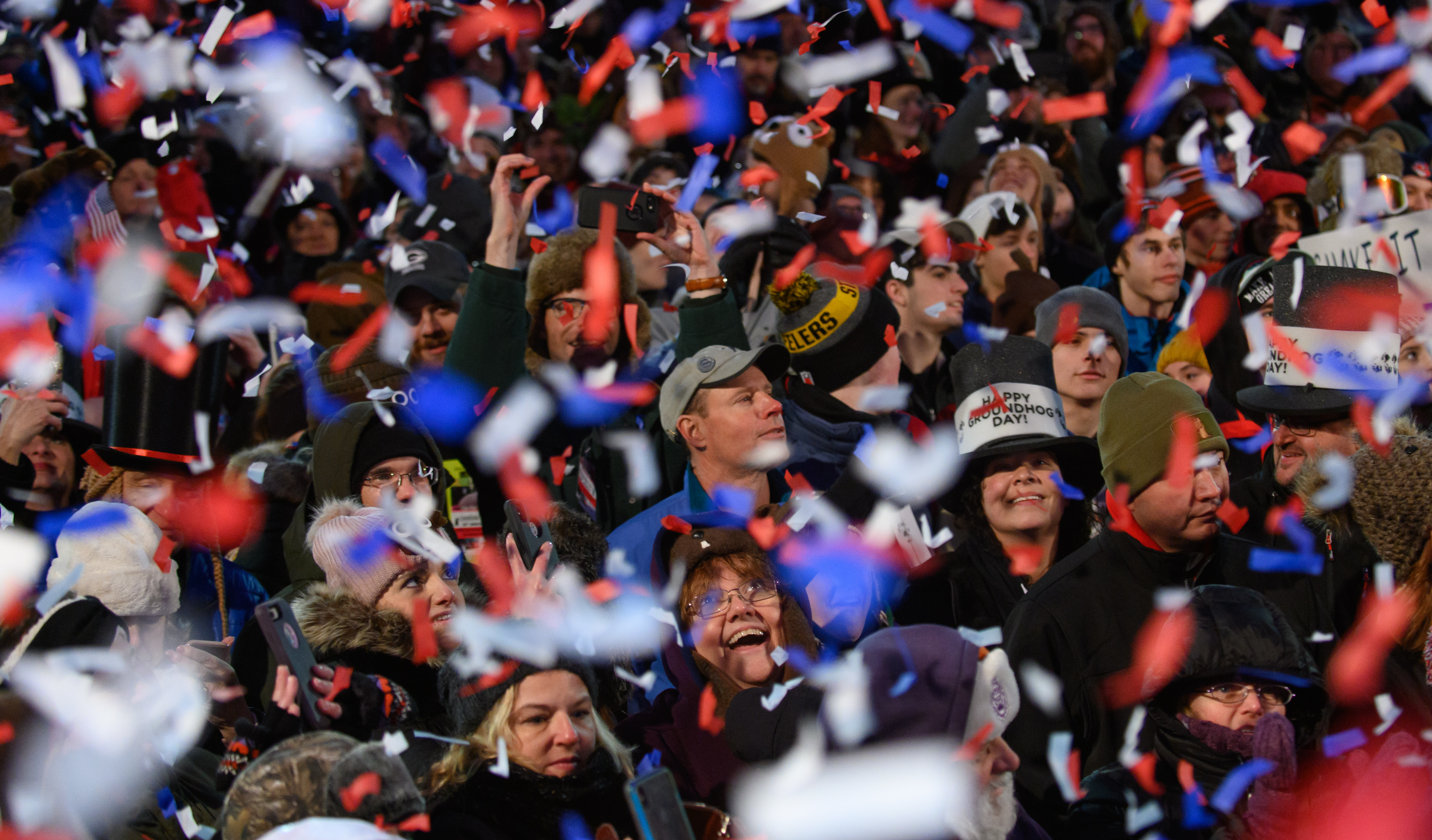 Crowd of mostly blurry faces with red, white, and blue confetti in foreground.