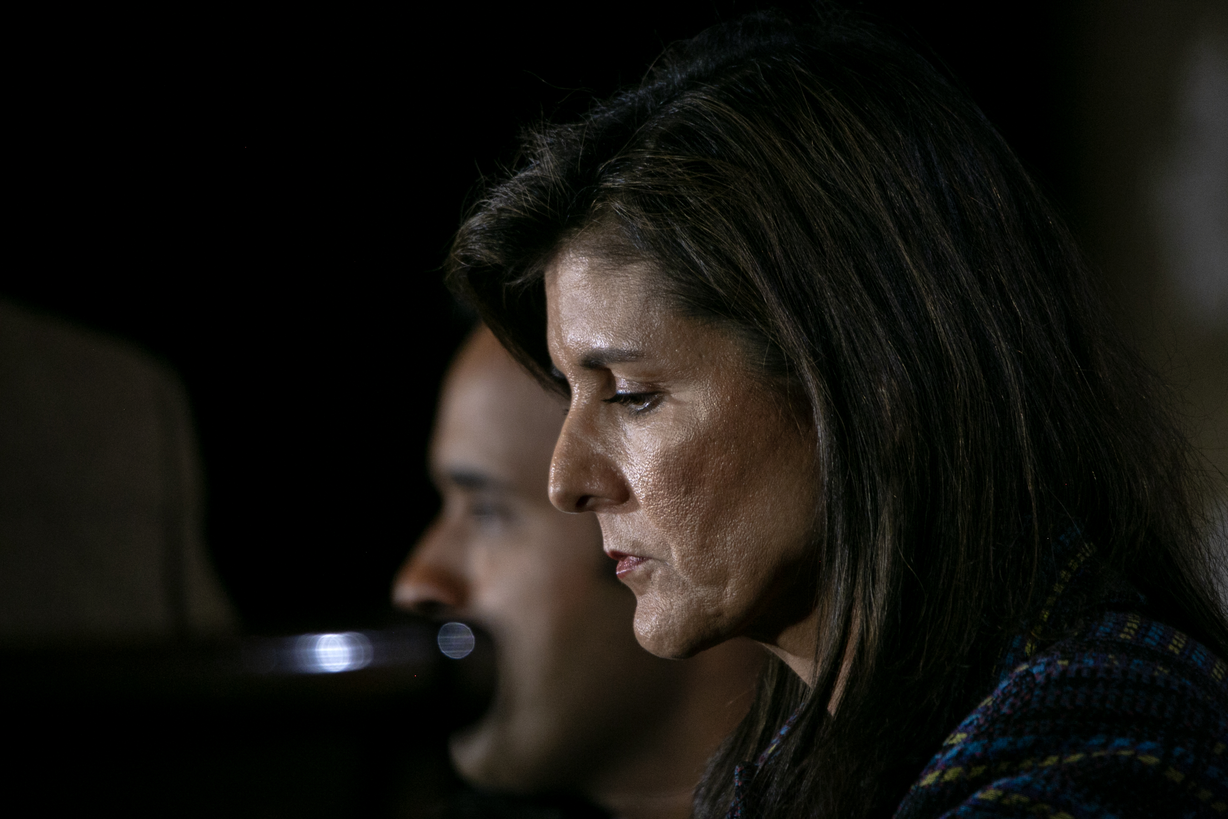 Nikki Haley looks subdued while preparing to speak into a microphone.